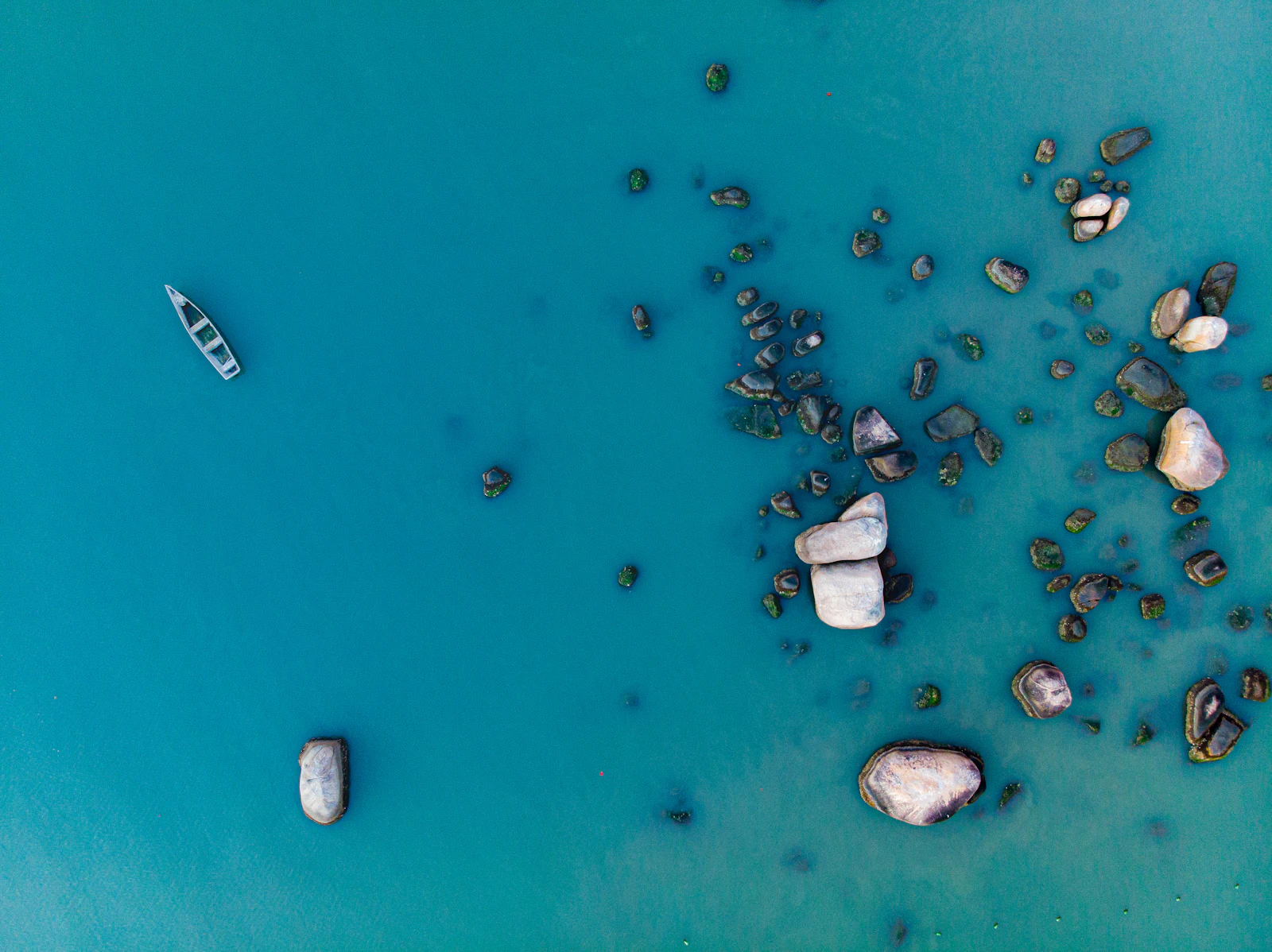 Barco sobre águas azul-turquesa entre rochas em Santo Antônio de Lisboa, Florianópolis